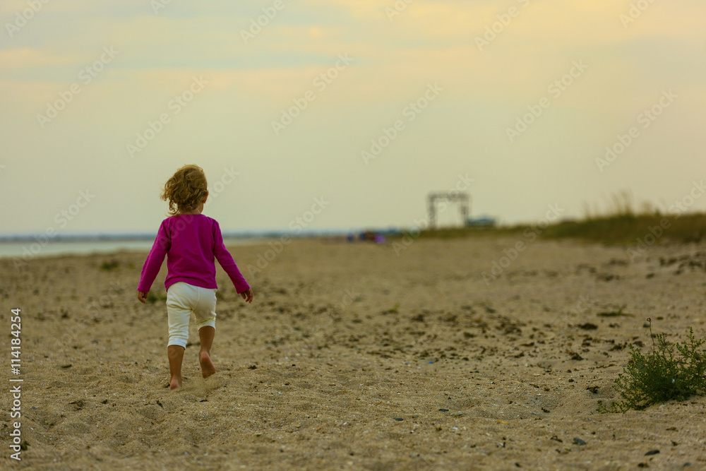The girl runs on the beach during sunset