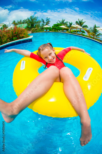 Little girl having fun in inflatable rubber circle at swimming pool. Family summer vacation, kid relax at pool. © travnikovstudio