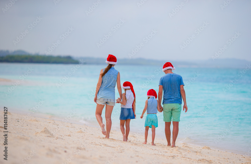 Happy family with two kids in Santa Hats on summer vacation. Christmas holidays with young family of four enjoying their sea trip