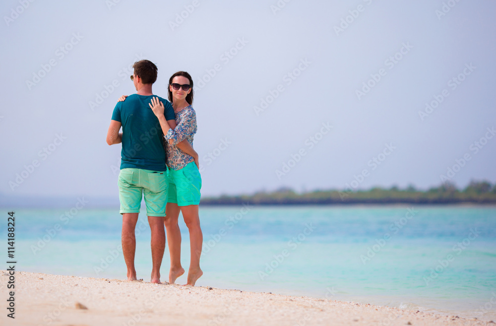 Young couple on white beach during summer vacation. Happy lovers enjoy their honeymoon at exotic island Young couple on white beach during summer vacation. Happy lovers enjoy their honeymoon at exotic island