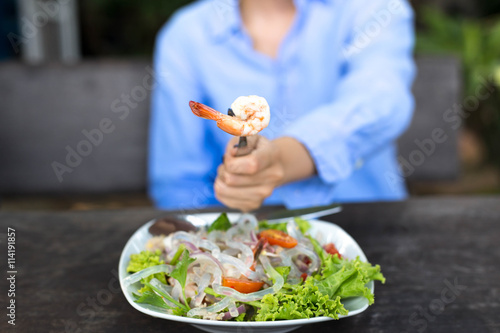 Fototapeta Naklejka Na Ścianę i Meble -  Hand holding fork with prawn and glass noodle salad