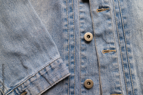 Close up aged denim texture. Old blue jeans jacket with buttons