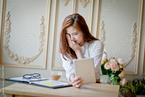 Woman with laptop watching scare movie on tablet computer.