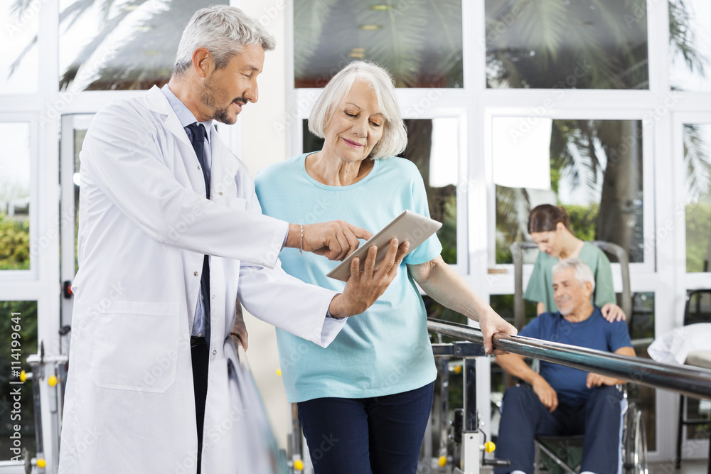 Doctor Showing Reports On Computer To Woman In Fitness Center Doctor Showing Reports On Computer To Woman In Fitness Center