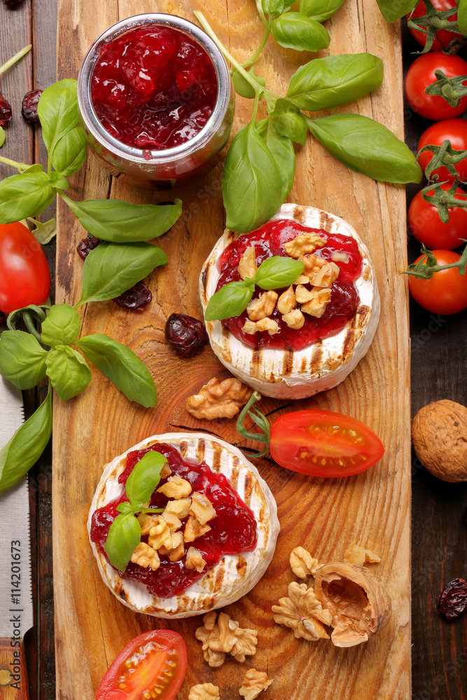 Grilled brie cheese with cranberry jam and walnuts on old wooden Grilled brie cheese with cranberry jam and walnuts on old wooden
