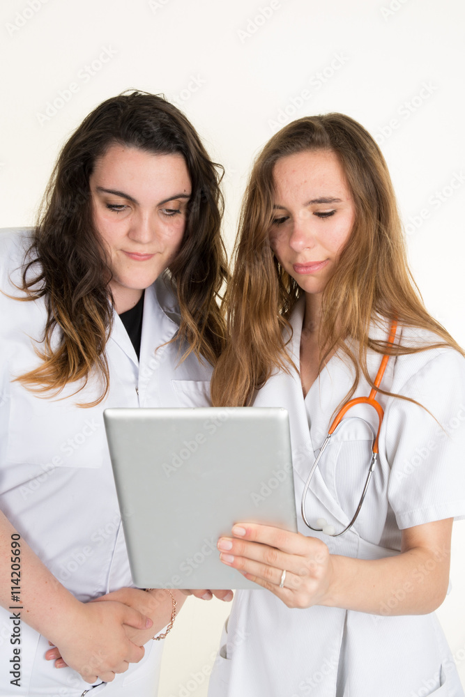 Two women doctors looking at tablet isolated on white Two women doctors looking at tablet isolated on white