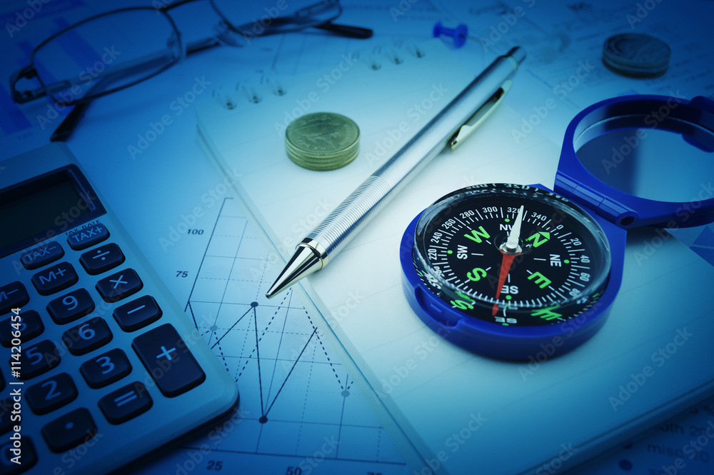 Compass, pen, glasses and coin on notebook, business vision conc Compass, pen, glasses and coin on notebook, business vision conc
