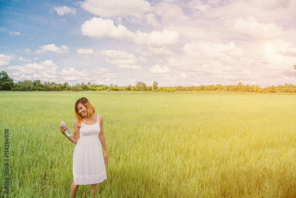 Woman drinking water on green meadow background.blue sky.