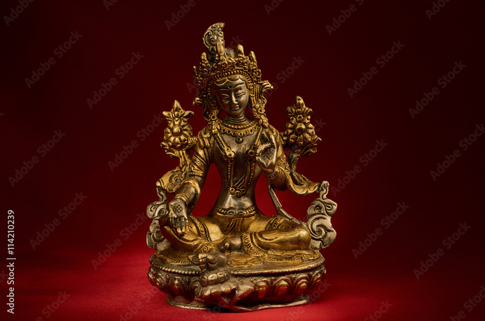 Statuette of Green Tara on a red background. Statuette of Green Tara on a red background.