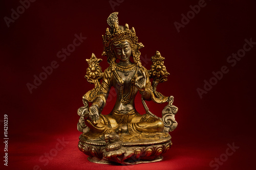 Statuette of Green Tara on a red background.
