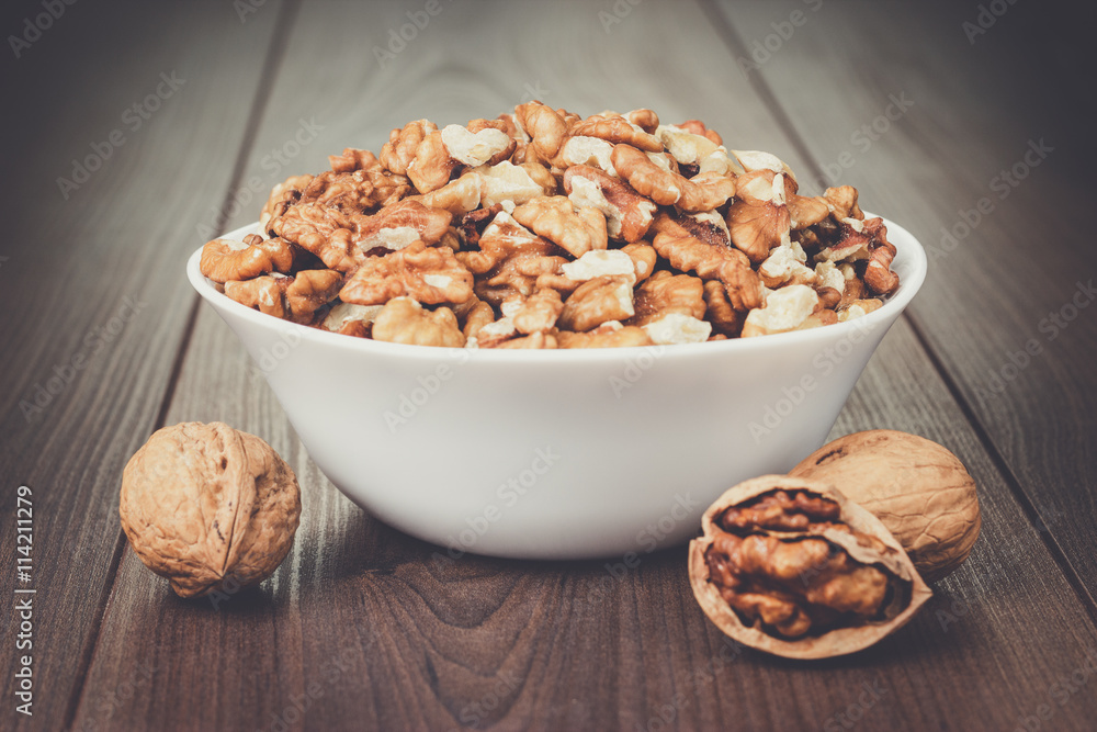 walnuts in the white bowl on brown wooden table walnuts in the white bowl on brown wooden table
