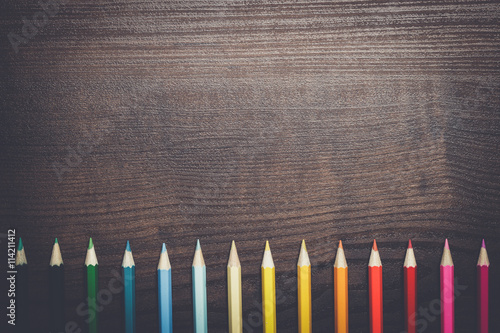 multicolored pencils on brown wooden table background