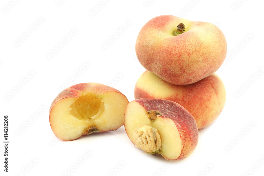fresh colorful flat peaches (donut peaches) and a cut one on a white background fresh colorful flat peaches (donut peaches) and a cut one on a white background
