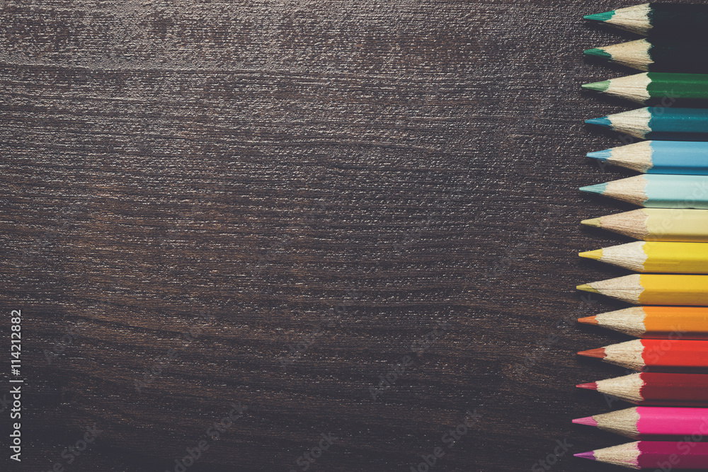 multicolored pencils on the dark brown wooden table background multicolored pencils on the dark brown wooden table background
