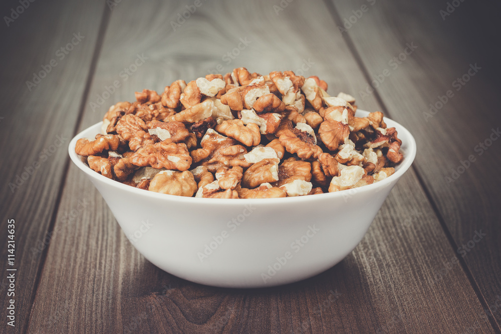 walnuts in the white bowl on brown wooden table walnuts in the white bowl on brown wooden table