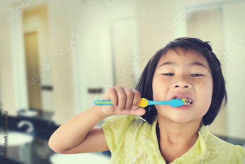 Little girl brushing her teeth isolated on toilet background