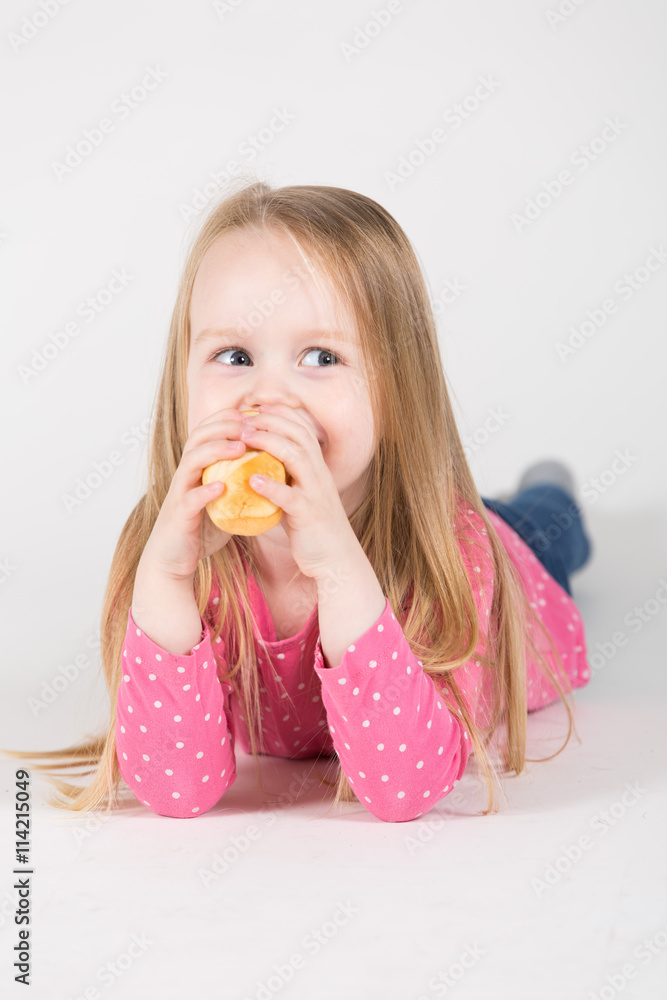 junges Mädchen liegt auf dem Boden und isst ein Brot junges Mädchen liegt auf dem Boden und isst ein Brot