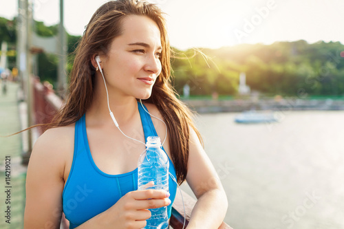 attractive young woman taking a water break while out on a run