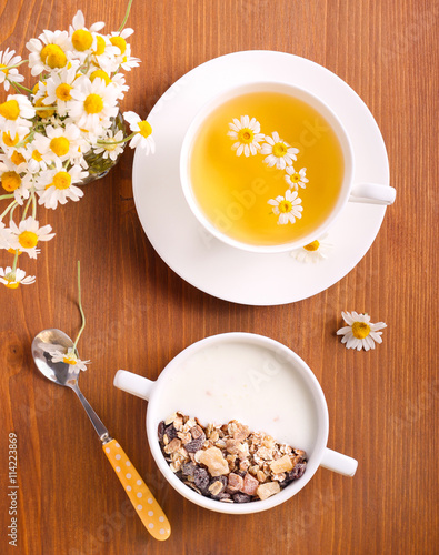 Muesli mix with yogurt in a bowl and chamomile tea,