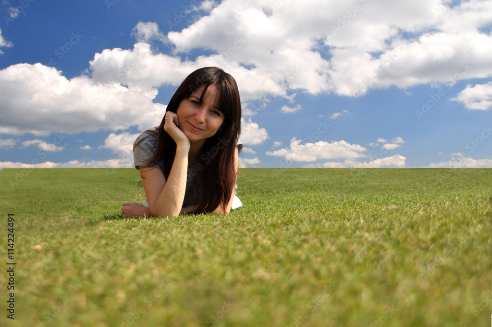 Happy girl lying on the grass against the sky