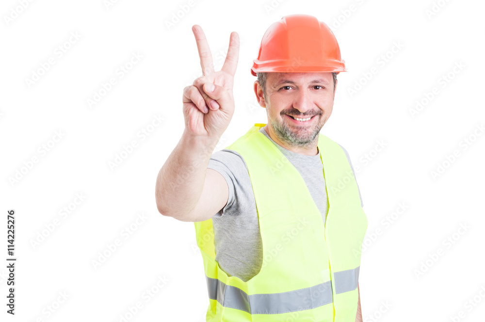 Handsome smiling workman or constructor with helmet showing vict