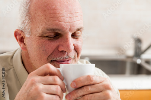 Man with eyes close holding coffee up to his nose