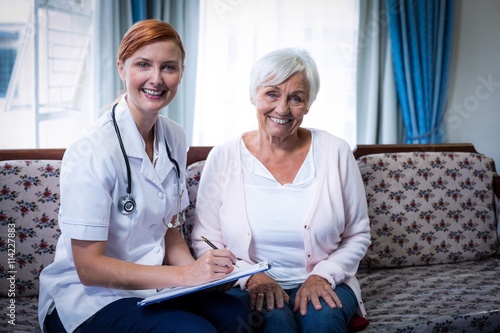 Billede på lærred Smiling doctor consulting with senior woman