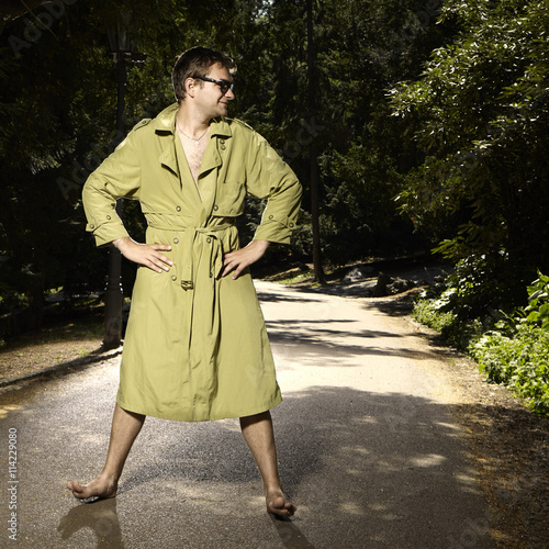 Fototapeta Pervert exhibitionist in coat in summer city park