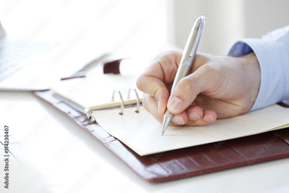 Making a list. Close-up shot of a businessman making a list to his diary while sitting at desk in office. Making a list. Close-up shot of a businessman making a list to his diary while sitting at desk in office.