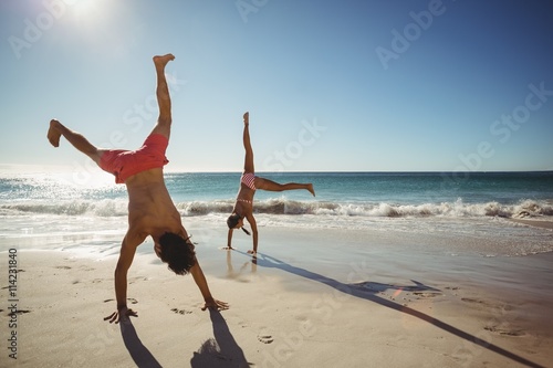 Fotografija Couple performing somersault on beach