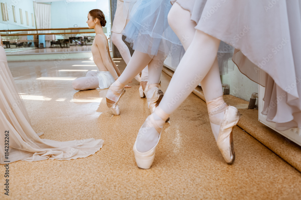 Fototapeta premium The close-up feet of young ballerinas in pointe shoes