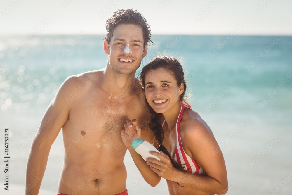 Young couple with sunscreen lotion on beach Young couple with sunscreen lotion on beach