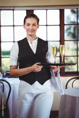 Portrait of waitress holding serving tray with champagne flutes 