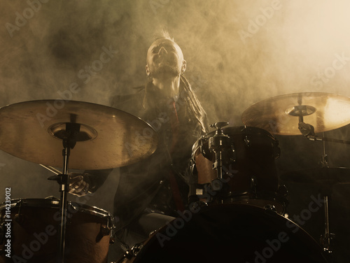 Silhouette drummer on stage. Dark background, smoke spotlights