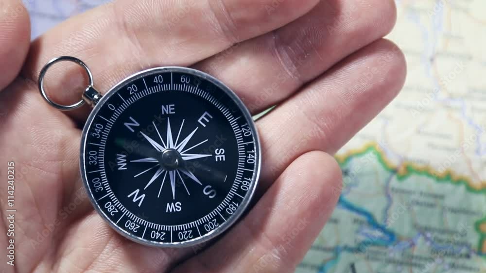 Hand holding a compass with swinging needle looking for North Hand holding a compass with swinging needle looking for North