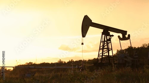 Oil rig is pumping the oil at sunset.