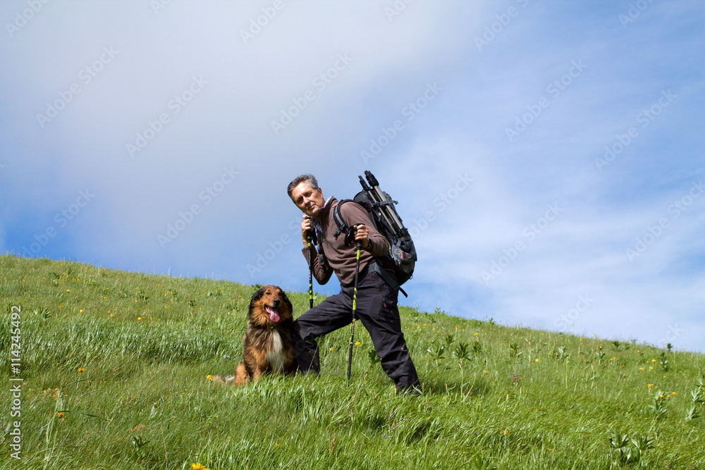 trekker standing on top of the hill with his dog