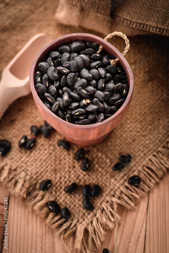  Vigna mungo or black beans in wooden cup with wooden scoop on s