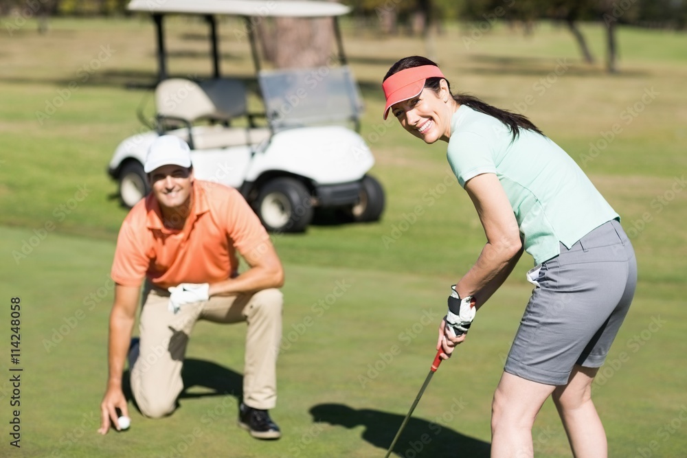 Obraz premium Portrait of smiling woman playing golf while standing by man 
