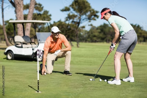 Woman playing golf while standing by man 