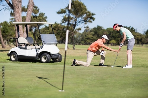 Man teaching woman playing golf 