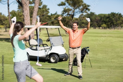 Happy golfer couple with arms raised 
