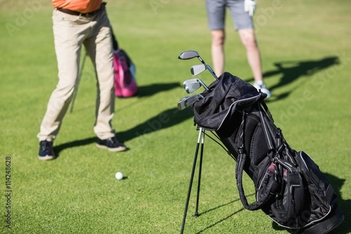 Couple playing golf with bag on foreground