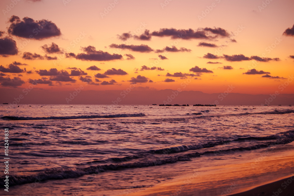 Sea waves during a colorful sunset over a beach.