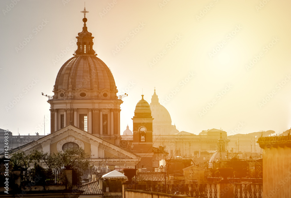 Urban landscape of Rome against the backdrop of an orange sunset.