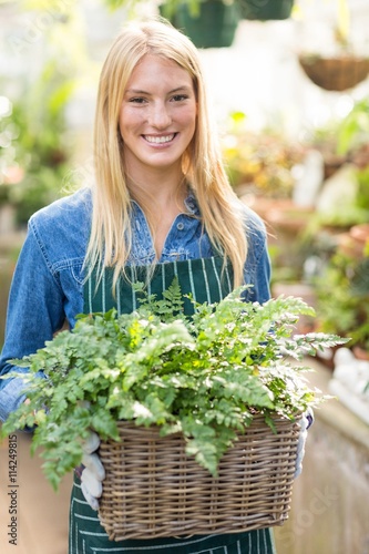 Beautiful woman holding plant in wicker basket 