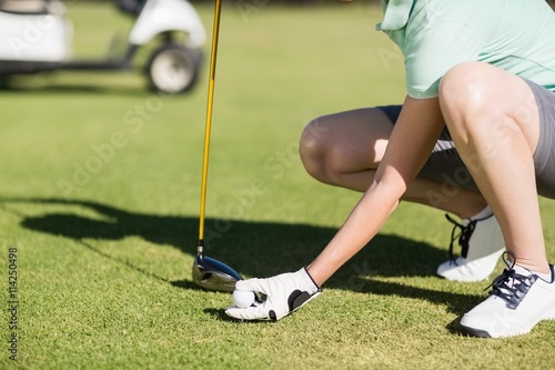 Low section of woman holding golf ball 