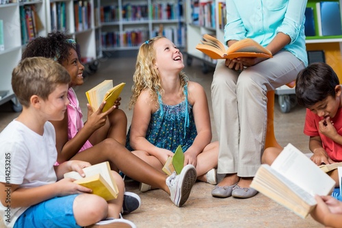 Low section of teacher with children reading books