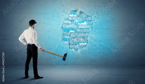 Business man hitting brick wall with huge hammer