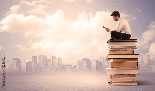 businessman with laptop sitting on books